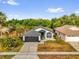 Aerial view of single-story home with grey roof, a two-car garage, and lush green surroundings at 11172 Pinewood Cove Ln, Orlando, FL 32817
