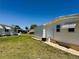 Side view of a mobile home with a well-maintained lawn, and blue sky at 129 Dogwood Trl, Leesburg, FL 34748
