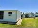 Exterior of a white mobile home featuring a well-maintained lawn, rock garden, and blue skies at 129 Dogwood Trl, Leesburg, FL 34748