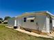 Exterior side view of a mobile home with vinyl siding, a brick foundation, and well-kept lawn at 129 Dogwood Trl, Leesburg, FL 34748