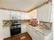 Well-lit kitchen boasts white cabinetry, granite countertops, stainless steel appliances, and tile backsplash at 129 Dogwood Trl, Leesburg, FL 34748