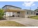 Rear exterior showcasing a covered parking area with a concrete driveway and a small bench at 1600 Hart Ln, Orlando, FL 32804