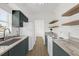 Updated kitchen features dark green cabinets, light countertops, stainless steel sink and floating shelves at 1600 Hart Ln, Orlando, FL 32804