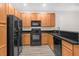 Modern kitchen with black appliances, warm wood cabinets, and sleek black countertops at 1880 Garden Sage Dr, Oviedo, FL 32765