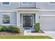 Close up of home entrance with black door flanked by windows and clipped hedges at 1940 Bell Creek Loop, Fruitland Park, FL 34731