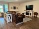 Cozy living room featuring hardwood floors, a leather couch, a fireplace, and a large TV at 1940 Bell Creek Loop, Fruitland Park, FL 34731