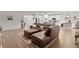 Spacious living room features a brown leather sectional, area rug, and an open layout to the kitchen at 1940 Bell Creek Loop, Fruitland Park, FL 34731