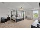 Spacious main bedroom with a four-poster bed, tray ceiling and large windows at 1940 Bell Creek Loop, Fruitland Park, FL 34731