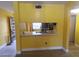 View of a kitchen with yellow walls from a room with wood-look flooring at 3475 Flossmoor Ave # 103, Orlando, FL 32822