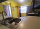 This kitchen boasts a double basin sink and yellow walls, with a window that adds brightness at 3475 Flossmoor Ave # 103, Orlando, FL 32822