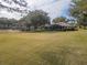 Expansive lawn with mature trees leading to a house with a screened-in patio at 39342 Harbor Hills Blvd, Lady Lake, FL 32159