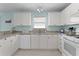 Clean kitchen featuring white cabinets, granite countertops, white appliances, and tiled floors at 424 Valverda Dr, The Villages, FL 32162