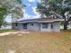 Backyard view of a gray home with windows and a sliding glass door, and sparse landscaping at 4680 Sw 142 Place Rd, Ocala, FL 34473