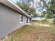 Backyard view showing the side of the gray home with a window and sliding glass door at 4680 Sw 142 Place Rd, Ocala, FL 34473