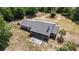 An aerial view displays a backyard with a shuffleboard court, framed by green trees and the home's covered patio at 5155 Holopaw Rd, St Cloud, FL 34773