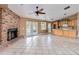 Bright living room with a brick fireplace, ceiling fan, and tile flooring leading into an adjacent kitchen space at 5155 Holopaw Rd, St Cloud, FL 34773
