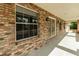 Close-up of a brick porch with large windows and a wooden door, showcasing architectural details and natural light at 5155 Holopaw Rd, St Cloud, FL 34773