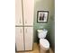 Bathroom with a toilet, tall linen closet and framed art on the pastel green walls at 102 Tangelo Cv, Leesburg, FL 34748