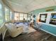 Bright sunroom with wood-look flooring, ceiling fan, windows, and comfortable seating area at 102 Tangelo Cv, Leesburg, FL 34748