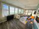 Bright sunroom with wood-look flooring, windows, ceiling fan, and comfortable seating area at 102 Tangelo Cv, Leesburg, FL 34748