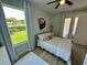 Bright bedroom featuring wood floors, neutral walls, a ceiling fan, and a large window with a green lawn view at 10640 Vista Del Sol Cir, Clermont, FL 34711