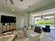 Spacious living area with a large TV, white sofa, ceiling fan, and view of the outdoor pool area at 10640 Vista Del Sol Cir, Clermont, FL 34711
