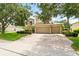 Exterior showcasing a three-car garage, brick driveway, and mature trees enhancing curb appeal at 1085 Harmony Ln, Clermont, FL 34711