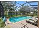 The stunning screened-in pool area features a waterfall, mature landscaping, and plenty of room for outdoor seating at 1085 Harmony Ln, Clermont, FL 34711