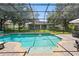 The crystal-clear, screened-in pool offers a serene space with mature landscaping and a tranquil waterfall feature at 1085 Harmony Ln, Clermont, FL 34711