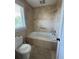 Bathroom with tiled tub/shower combo, updated fixtures, and neutral color scheme at 12765 Se 143Rd Ave, Ocklawaha, FL 32179