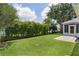 Spacious backyard featuring a lush lawn, manicured shrubs, and a screened lanai at 1305 Guerra Ave, The Villages, FL 32159