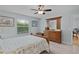 Light-filled bedroom with wood dresser, ceiling fan and large window at 1305 Guerra Ave, The Villages, FL 32159