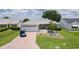 Charming single-story home with a well-manicured lawn, paver driveway, and a blue golf cart at 1305 Guerra Ave, The Villages, FL 32159