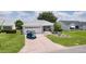 Charming front exterior with paved driveway, landscaping, and a blue golf cart at 1305 Guerra Ave, The Villages, FL 32159