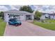Charming front exterior with paved driveway, landscaping, and a blue golf cart at 1305 Guerra Ave, The Villages, FL 32159