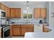 Kitchen features stainless steel appliances, wood cabinets, light blue countertops, and a double basin sink at 1305 Guerra Ave, The Villages, FL 32159