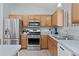 Kitchen features stainless steel appliances, wood cabinets, and light blue countertops at 1305 Guerra Ave, The Villages, FL 32159