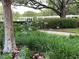 Lush landscaping featuring a large tree, vibrant flowers, manicured hedges, and walking paths for relaxation at 1305 Guerra Ave, The Villages, FL 32159
