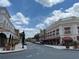 A vibrant town center street with storefronts, sidewalks, and palm trees, perfect for shopping and dining at 1305 Guerra Ave, The Villages, FL 32159