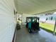 View of covered carport, with space for golf cart, showing privacy wall and neatly kept lawn at 313 Palo Verde Dr, Leesburg, FL 34748