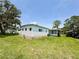 Side view of home highlighting the well-maintained lawn and mature trees at 313 Palo Verde Dr, Leesburg, FL 34748