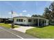Single-story home with covered carport, showcasing a neat lawn and an American flag at 313 Palo Verde Dr, Leesburg, FL 34748