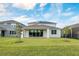 The backyard features lush grass and a view of the home's back exterior with solar panels on the roof at 6066 Arbor Watch Loop, Orlando, FL 32829