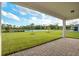 A view of the covered back porch and the grass yard with a pond and trees, creating a relaxing view at 6066 Arbor Watch Loop, Orlando, FL 32829