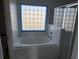 Bright bathroom featuring a tub and shower combination, with a glass block window at 6608 Madeira Ave, Lakeland, FL 33811