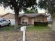 Charming single-story home featuring a well-manicured lawn, attached garage, and mature trees shading the front at 6616 Shepherd Oaks St, Lakeland, FL 33811