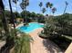 Expansive community pool with brick patio, surrounded by lush landscaping and tall palm trees at 7320 Westpointe Blvd # 531, Orlando, FL 32835