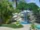 A charming rock waterfall feature spilling into a pool, surrounded by tropical plants and lush landscaping at 7320 Westpointe Blvd # 531, Orlando, FL 32835