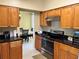 Galley style kitchen with wood cabinets, stainless steel appliances, and black granite countertops at 904 W Charing Cross Cir, Lake Mary, FL 32746