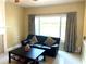 Bright living room with tile flooring, black leather sofa, and a large window for natural light at 904 W Charing Cross Cir, Lake Mary, FL 32746